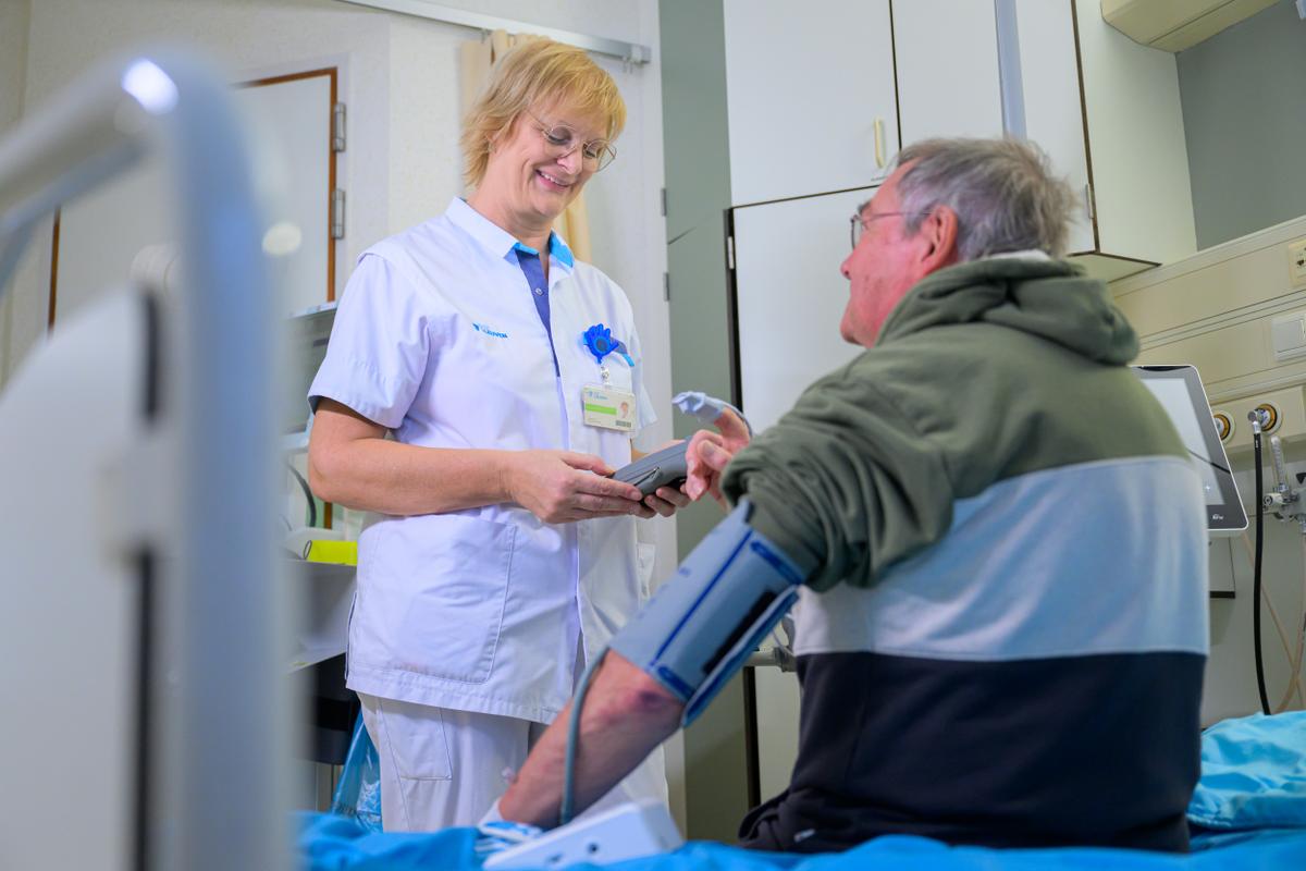 Verpleegkundige neemt de bloeddruk van patiënt, een oudere man